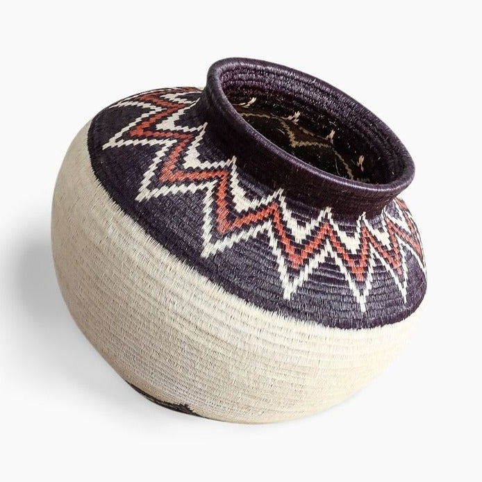 woven basket with zigzag pattern on a white background