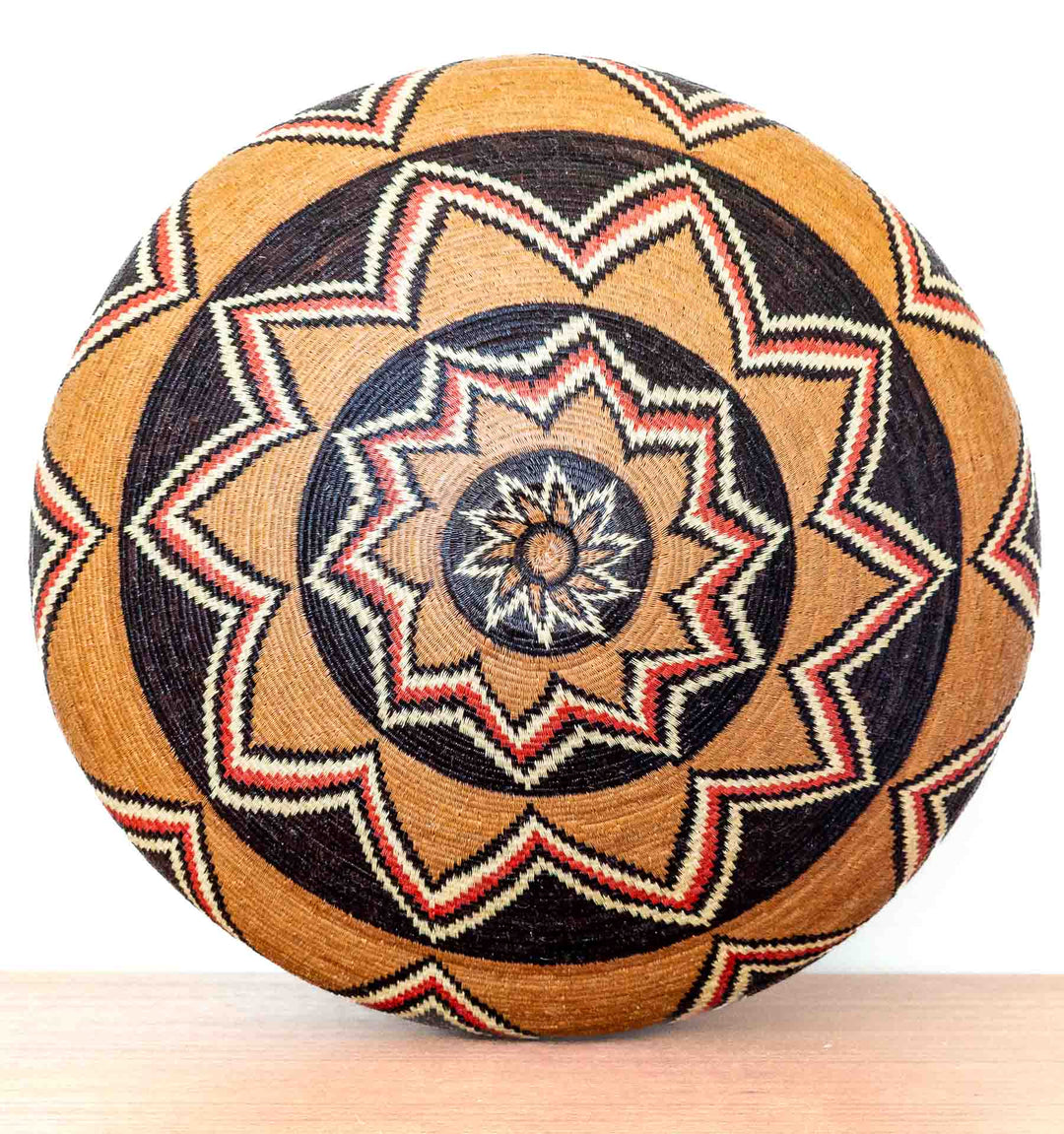 Bottom view of Ember Sunburst Wounaan basket with starburst motif in red, ivory, and black