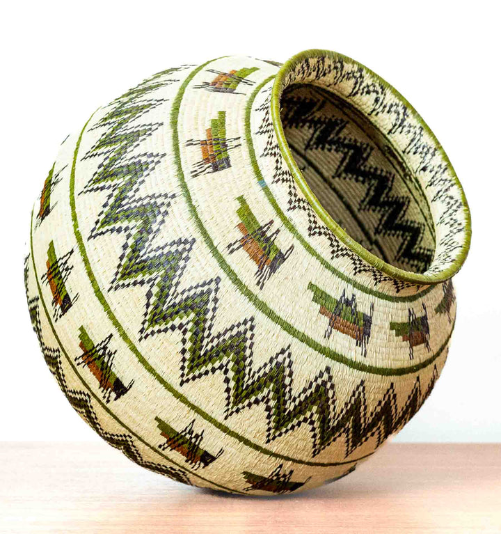 Side view of large round Wounaan basket with zigzag and insect designs.
