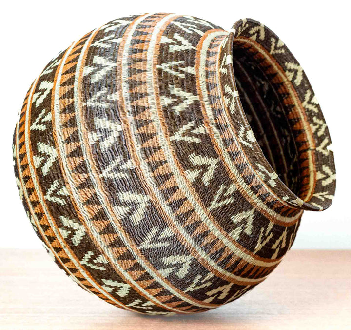 Angled side view of Ember Glow Chevron Wounaan basket showing round form.