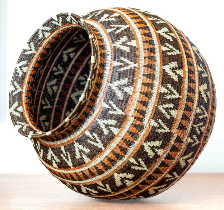 Angled side view of Ember Glow Chevron Wounaan basket showing round form.