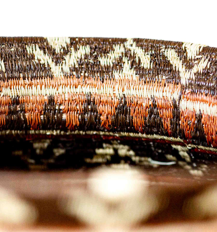 Close-up of rim and woven chevron design in orange, brown, and ivory on a Wounaan basket