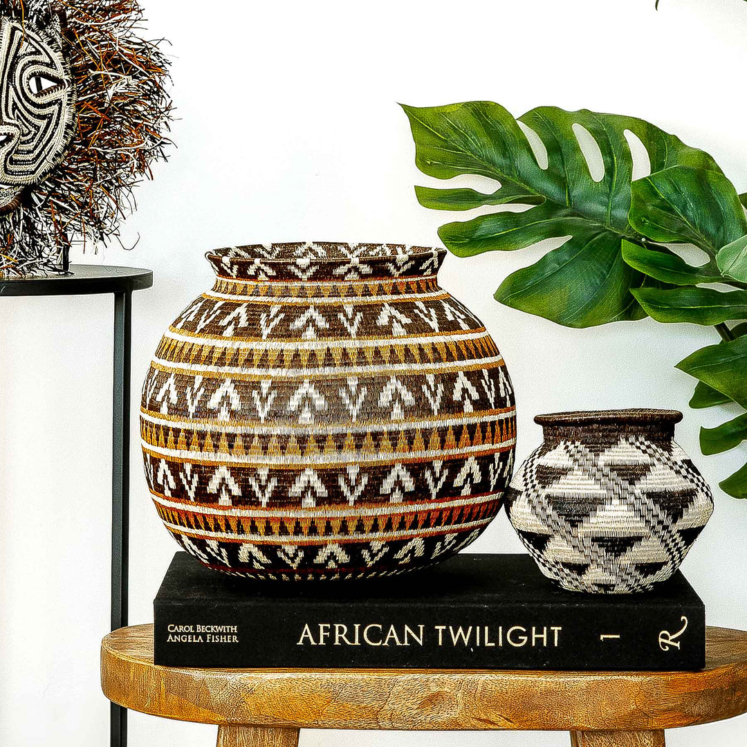 Full front view of handwoven Wounaan basket in ember tones on a wooden surface.