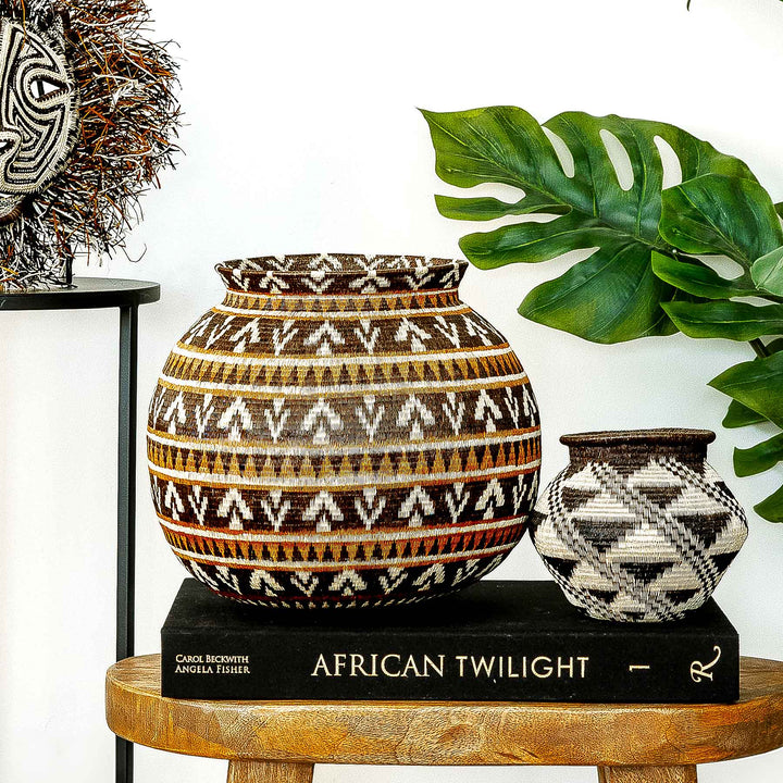 Full front view of handwoven Wounaan basket in ember tones on a wooden surface.