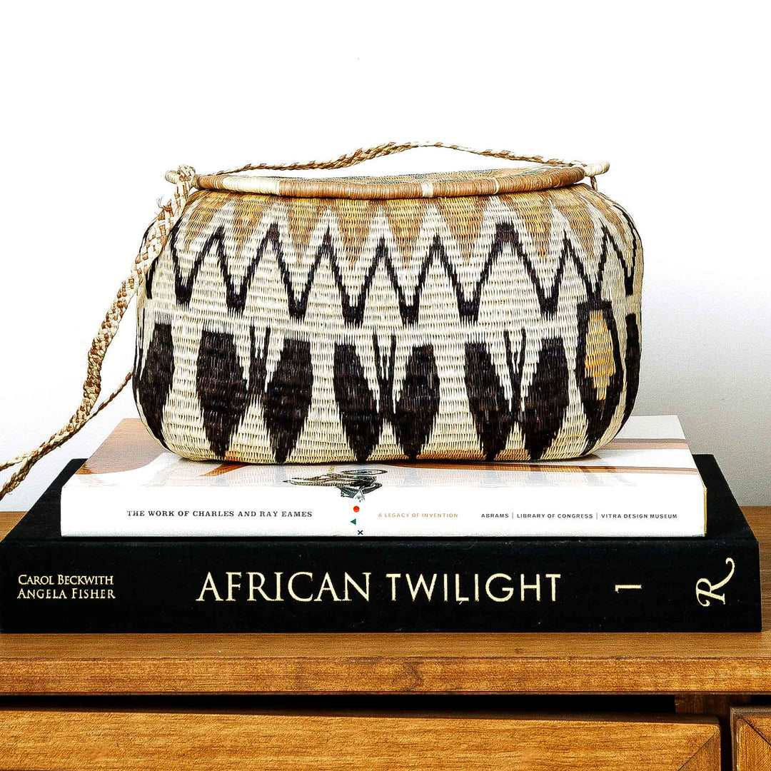 Golden peaks Wounaan basket purse displayed on stacked art books