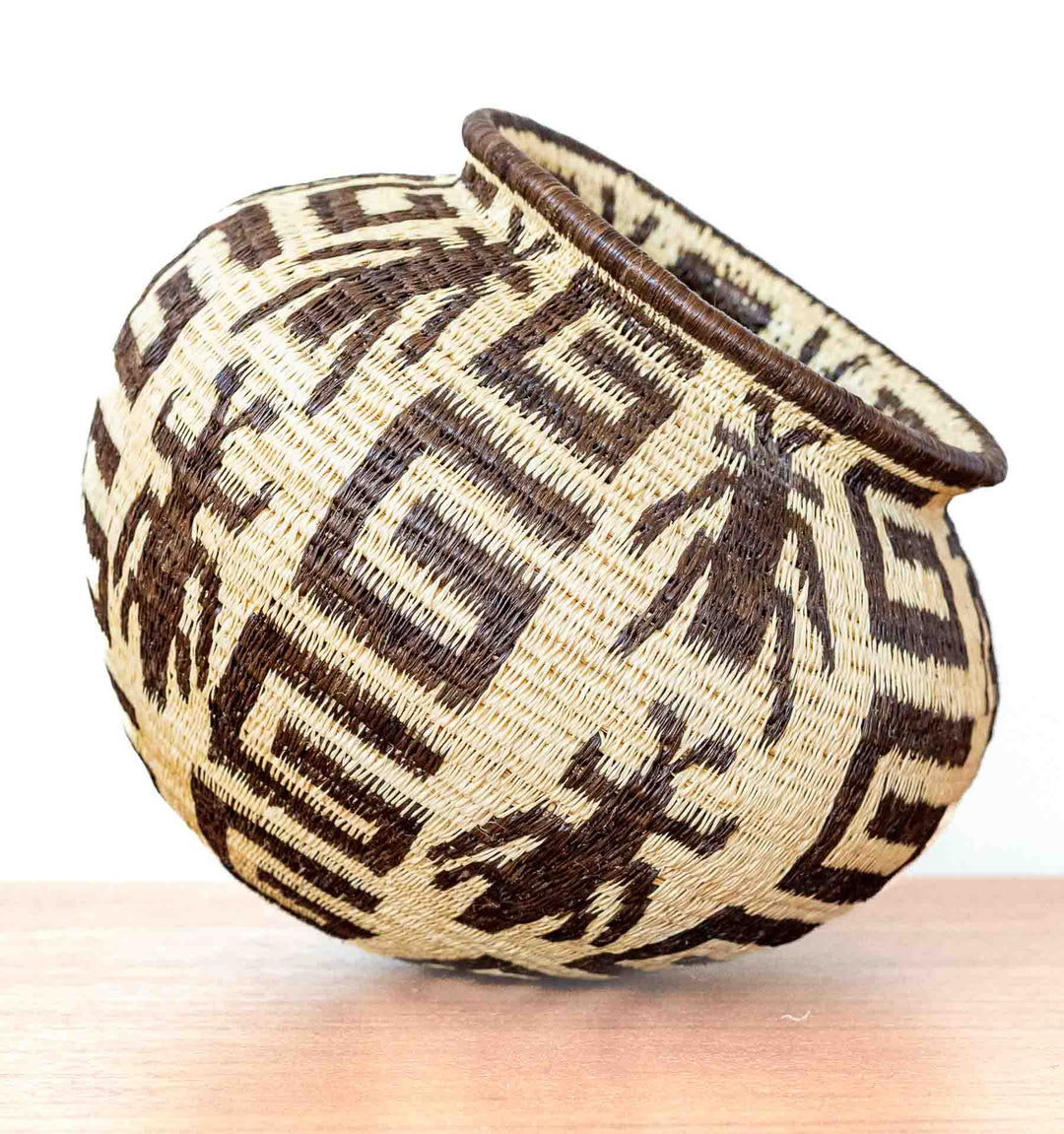 Side view of handwoven basket showing insect motif framed in geometric patterns.