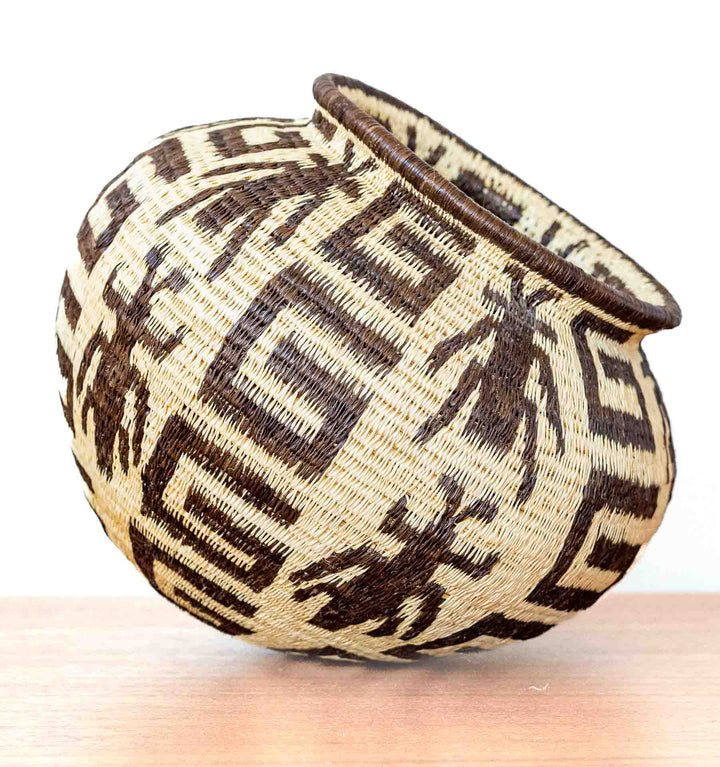 Side view of handwoven basket showing insect motif framed in geometric patterns.