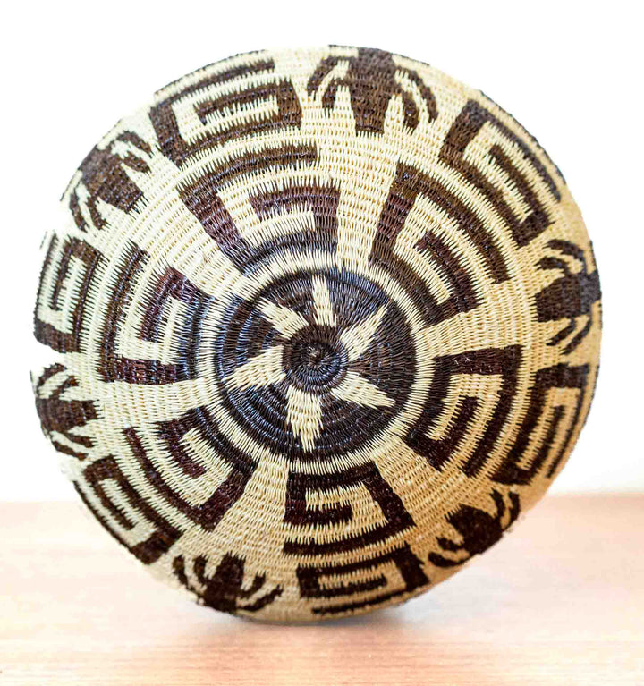 Bottom of basket with radiating star and insect symbols in woven palm fiber