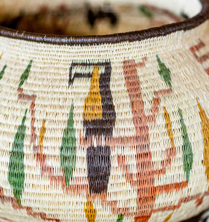 Detailed view of toucan motif in yellow, black, and green, woven into natural palm fiber