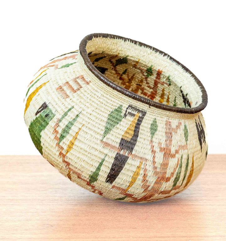 Handwoven basket featuring toucans perched among stylized rainforest plants.