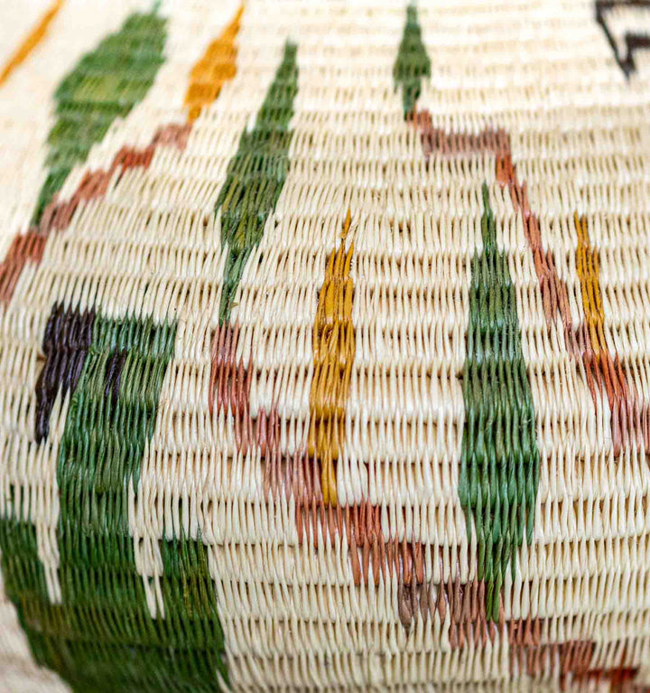 Intricate woven palm fiber with green, yellow, and rust leaf motifs.