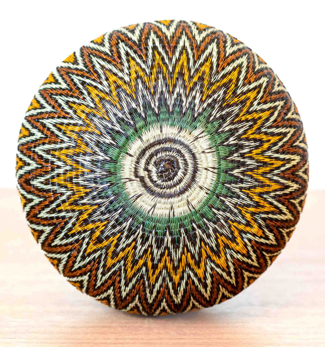 Bottom view of Rainforest Chevron Basket with radiating starburst pattern in green and gold.