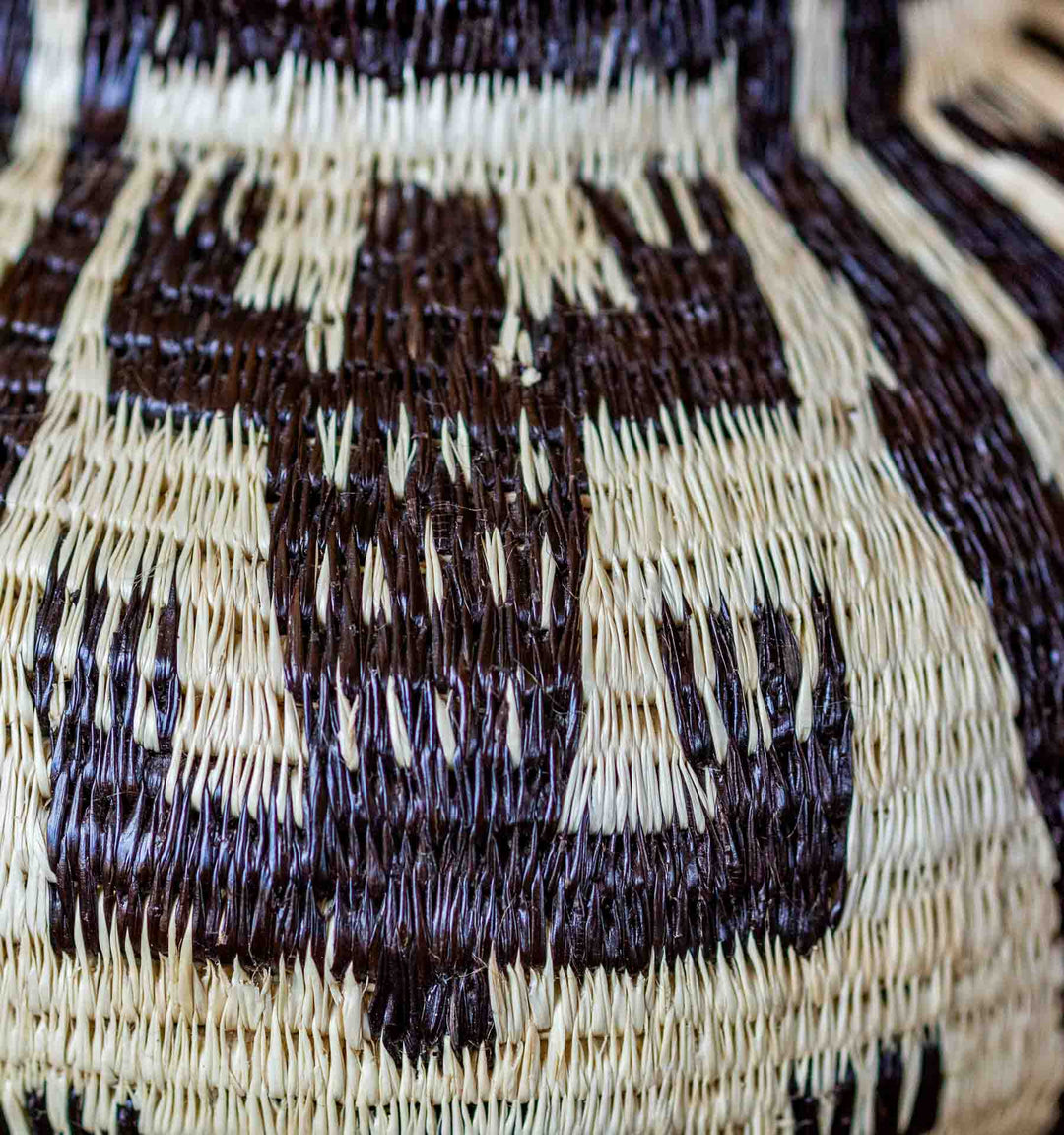 Close-up of handwoven Wounaan basket showing crocodile motif details in black and natural fiber.