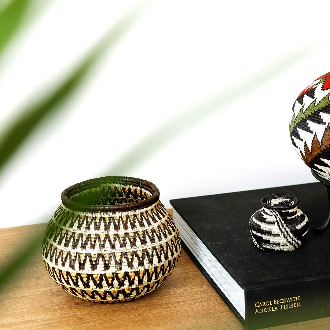 Sunburst Wave Wounaan basket displayed on console table, handwoven in Panama from palm fibers with geometric design.