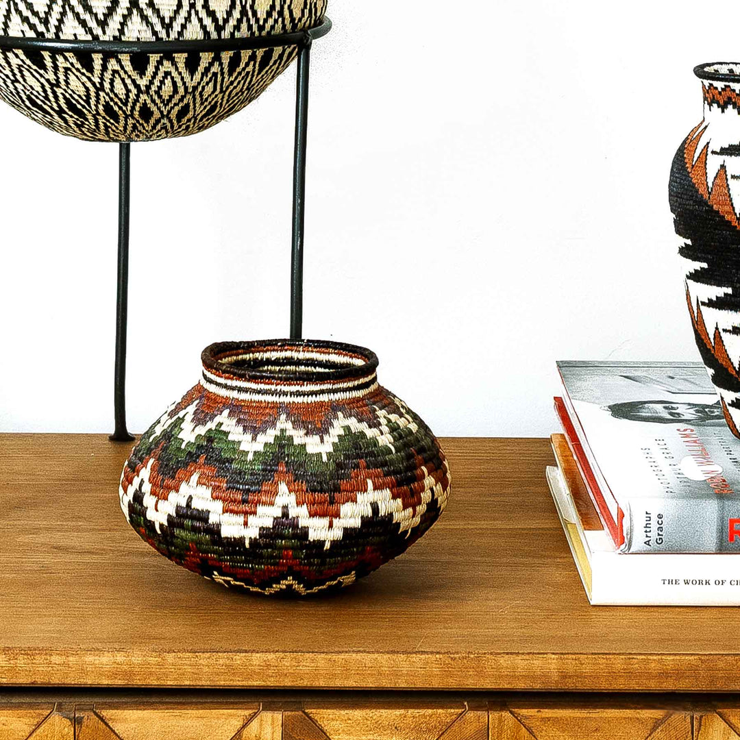 Rainforest Chevron Wounaan basket displayed on console table, handwoven in Panama with colorful palm fiber chevron design.