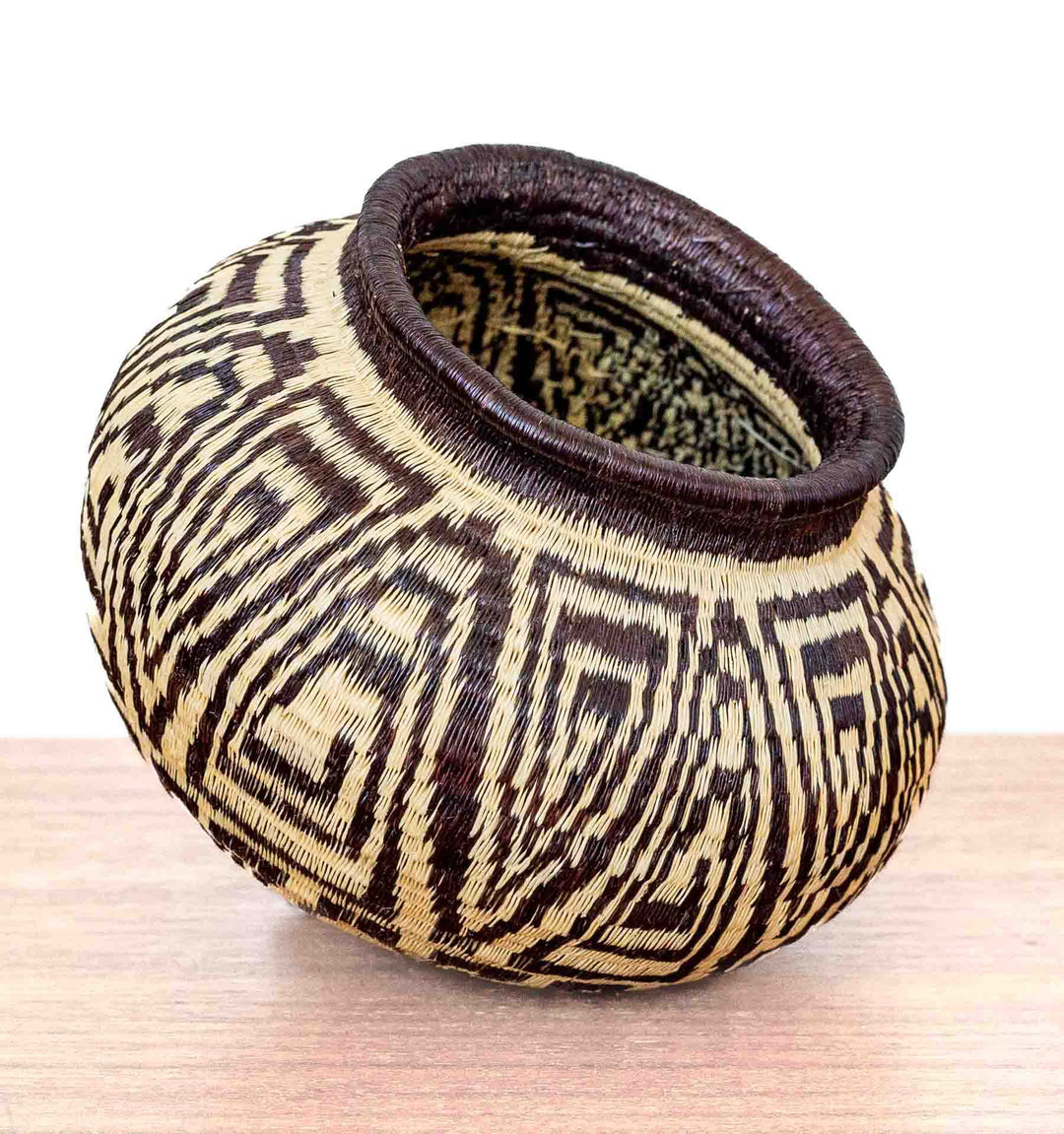 Wounaan basket from Panama handwoven with labyrinth motif in black and ivory tones, tilted for side display.