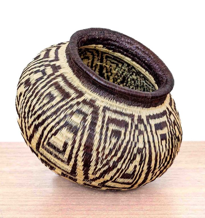 Wounaan basket from Panama handwoven with labyrinth motif in black and ivory tones, tilted for side display.
