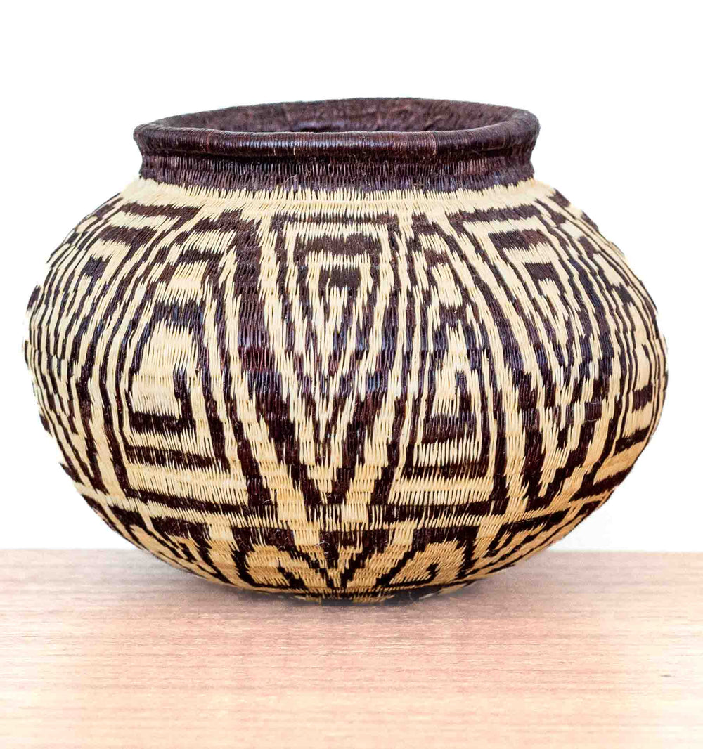 Handwoven Wounaan basket with rounded form and repeating labyrinth pattern, crafted in Panama from dyed palm fibers