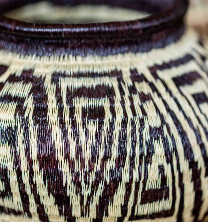 Detail view of handwoven Panamanian Wounaan basket with bold geometric design in natural palm fiber.