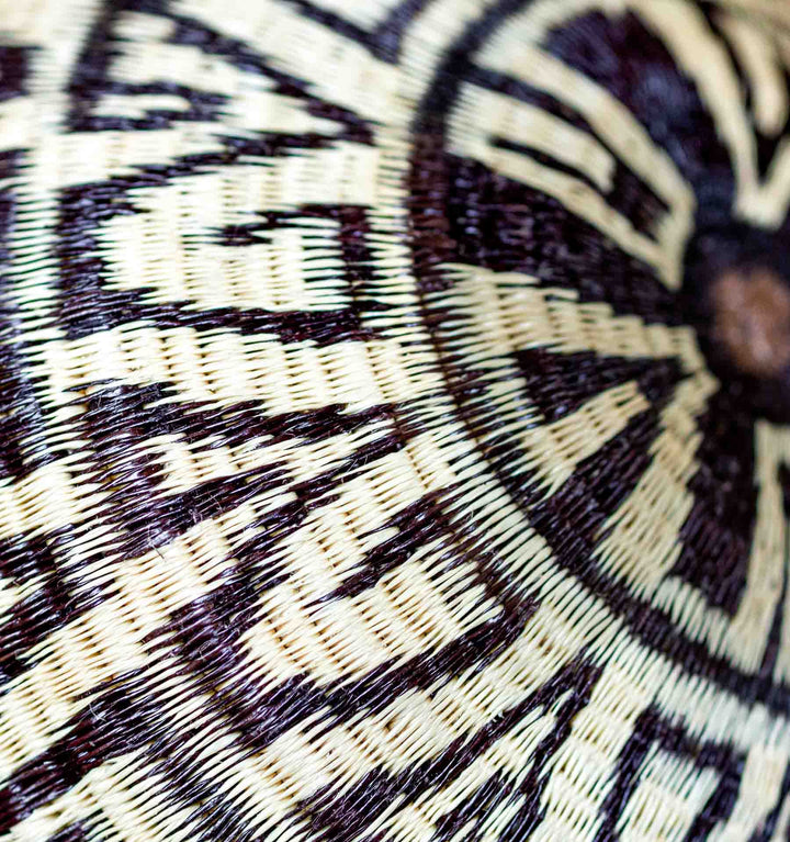 Close-up of Wounaan basket showing intricate labyrinth-style geometric pattern in black and ivory palm fiber.