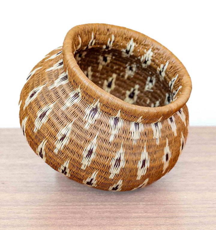Handwoven Wounaan basket with rounded body and repeating flame motif, crafted in Panama from dyed palm fibers.