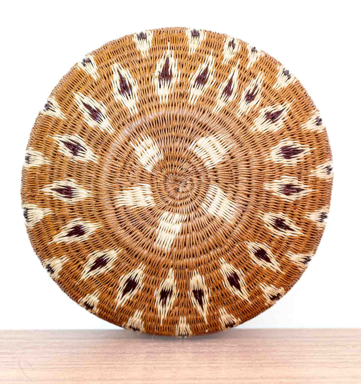 Overhead view of Wounaan woven basket from Panama showing intricate flame-like star pattern in natural palm fiber.